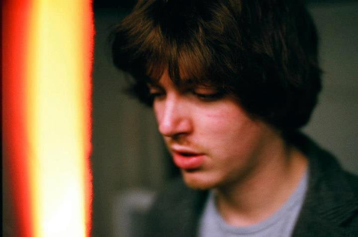 A softly focused portrait of Robin Fisher beside a vertical orange light leak.
